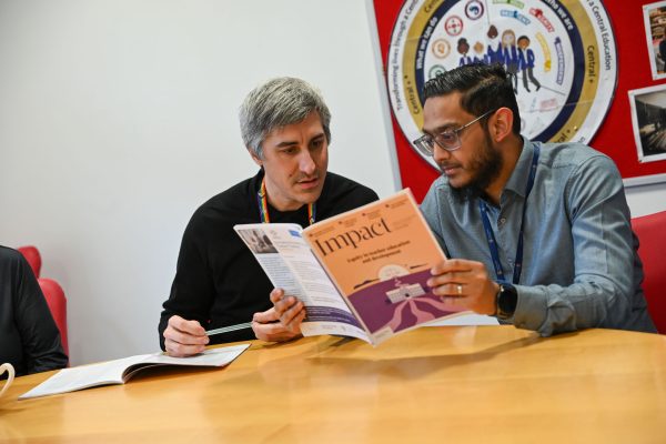 Two teachers reading and discussing issue of Impact issue 26: Equity in teacher education and development